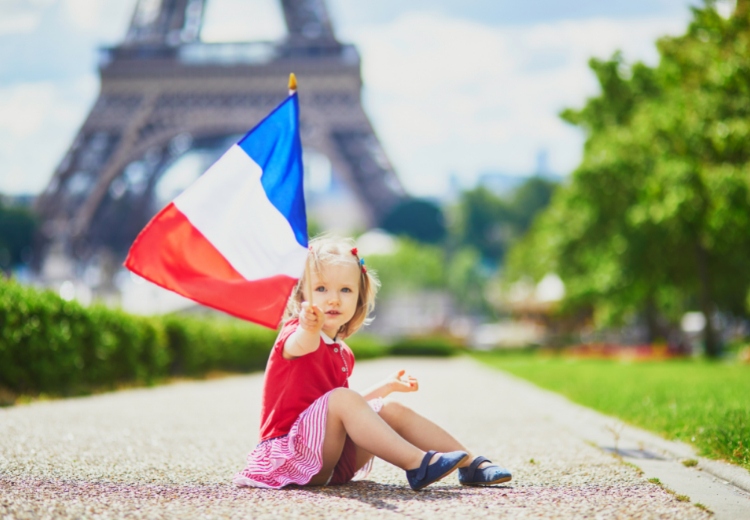פריז - ילדה קטנה יושבת מול מגדל אייפל עם דגל צרפת
