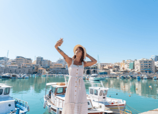 אישה מצלמת סלפי על רקע הנמל בכרתים