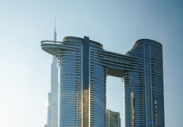 בניין Sky Views בדובאי – שני מגדלים מחוברים בגשר זכוכית ייחודי עם תצפית על קו הרקיע וברקע בורג' ח'ליפה.