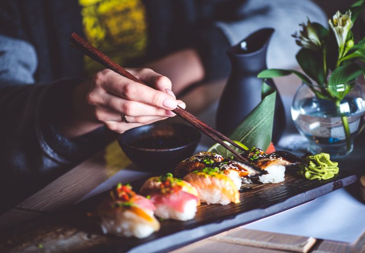 סועדת במסעדה יפנית אוכלת סושי עם מקלות