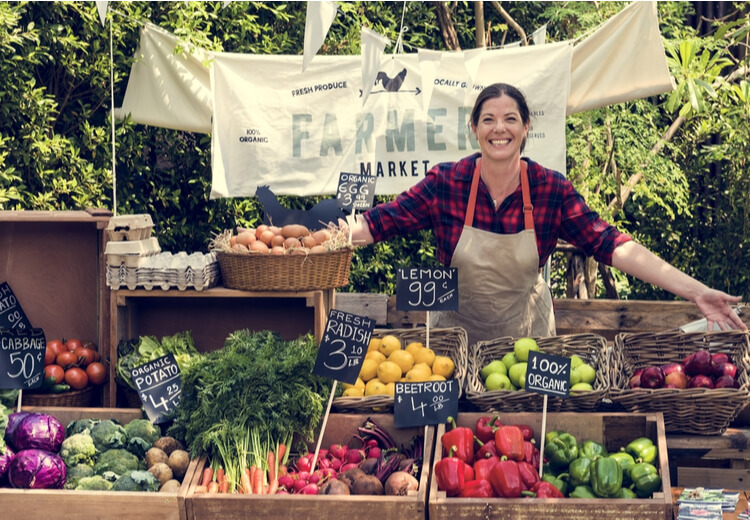 אישה מצטלמת בדוכן ירקות ופירות בשוק
